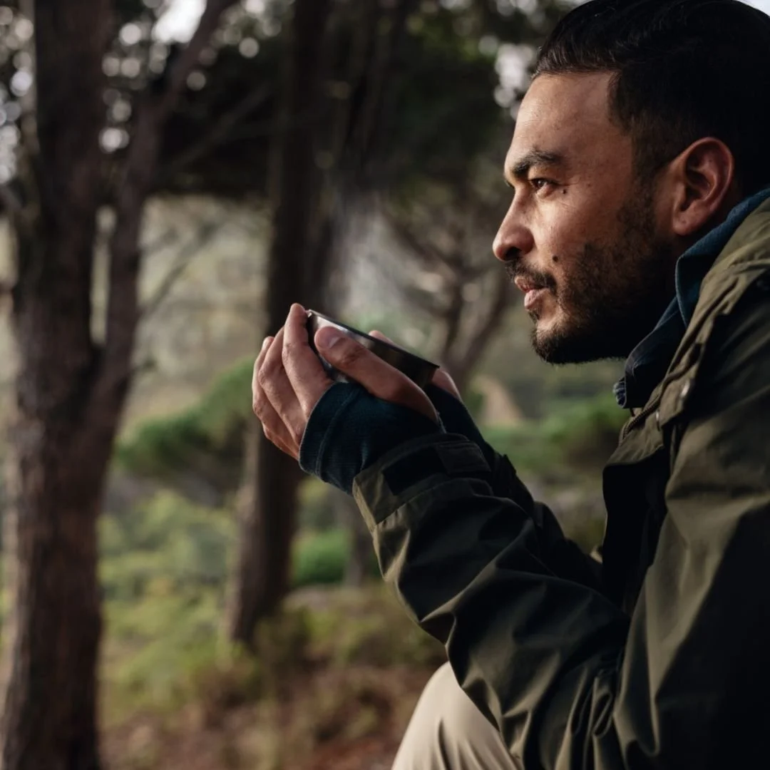 A man holding a cup of mushroom tea outdoors