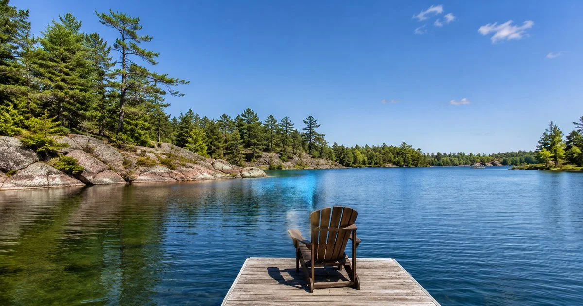 Kahshe Lake on a clear summer day with granite shoreline, windswept pines and a wooden dock, South Muskoka near Gravenhurst, Ontario