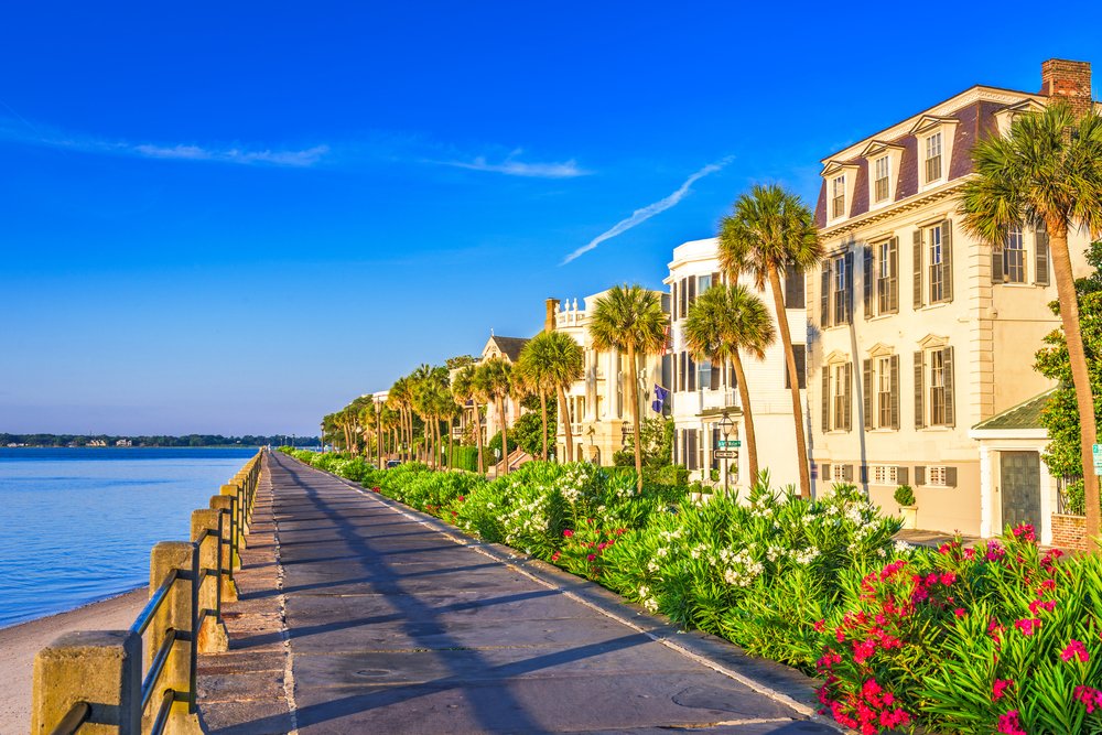 A path with palm trees beside the historic Battery buildings along the water