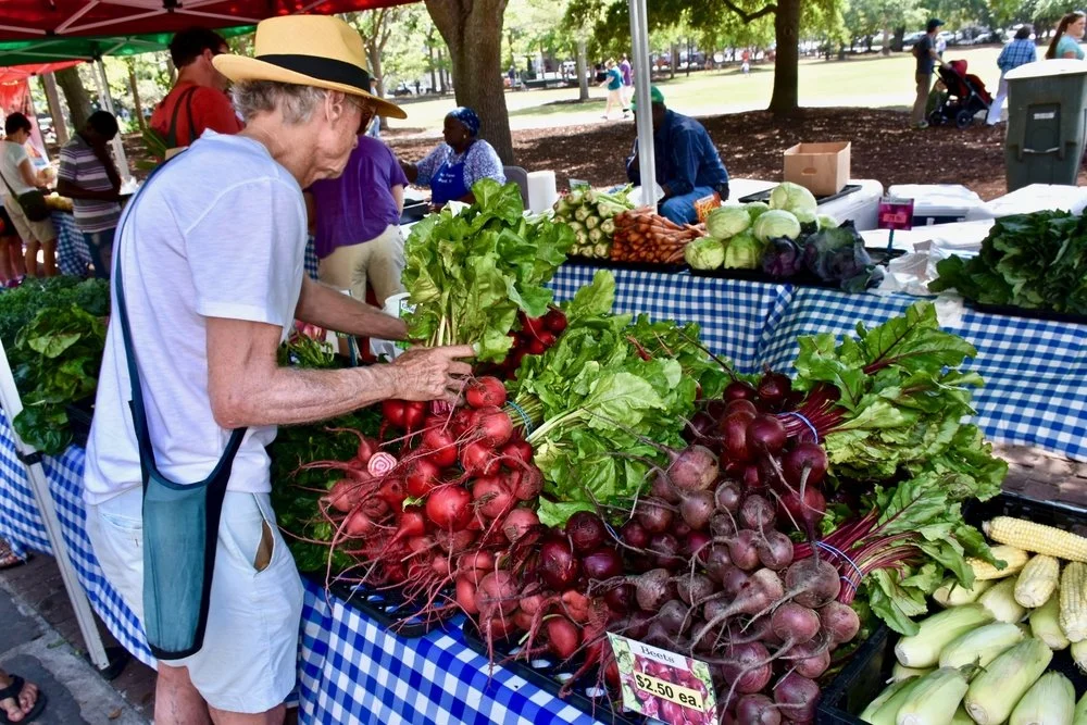 An old person selling vegetables at The Charleston Farmers Market