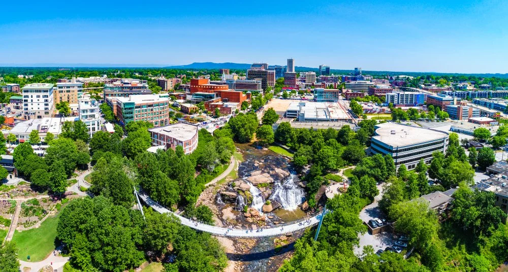 A drone shot of Downtown Greenville with the Reedy River running through it