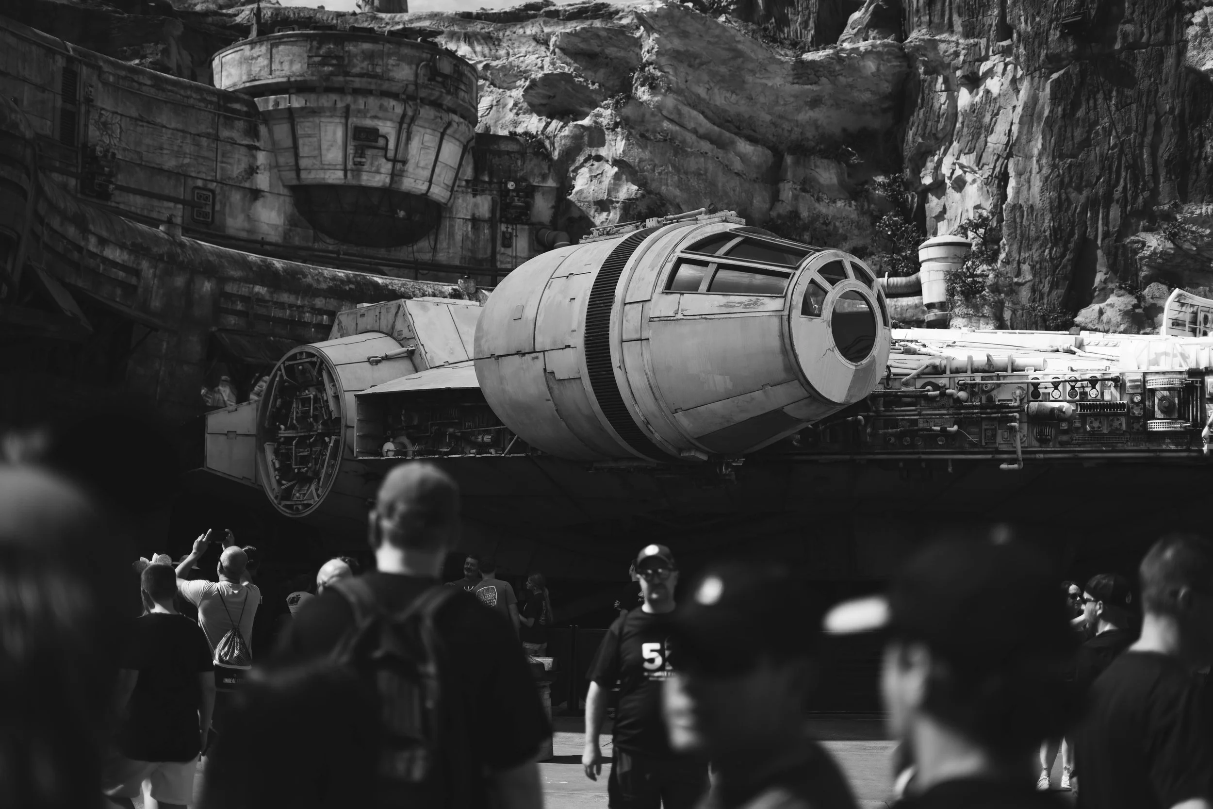 A large spaceship from the Star Wars universe, the Millennium Falcon, on display in a museum with visitors observing it.