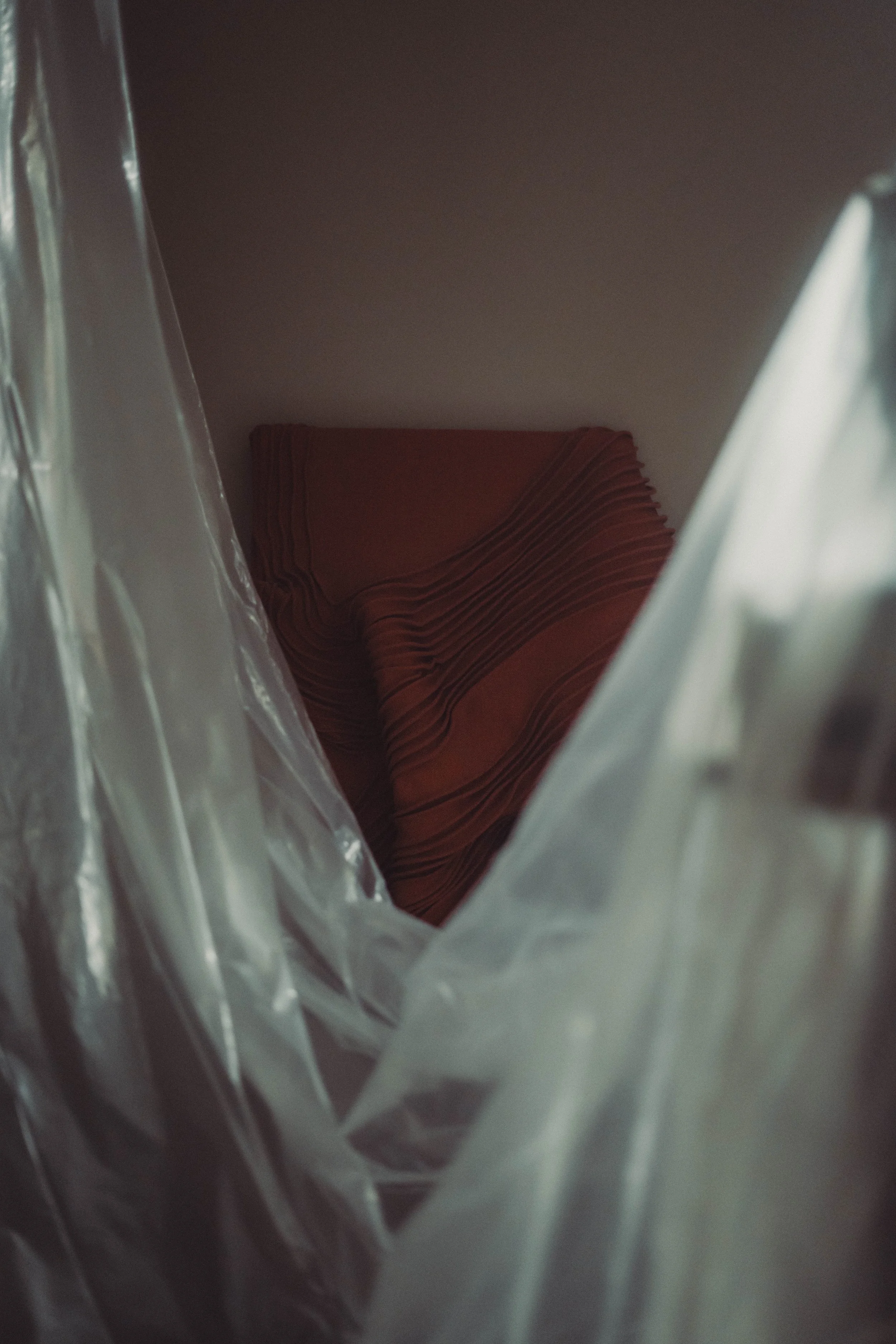 View inside a plastic shopping bag showing a neatly folded brownish-orange cloth.