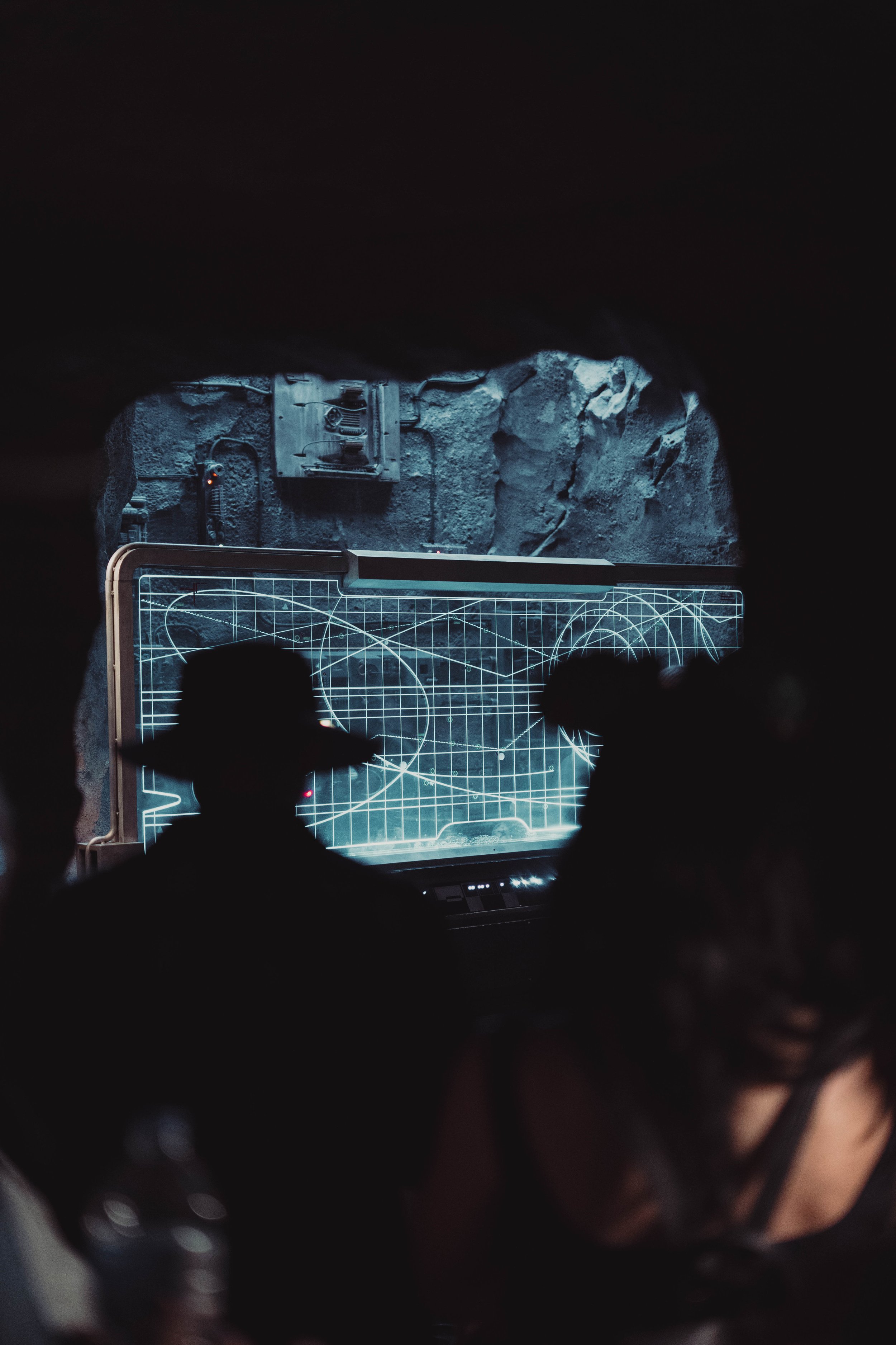 People watching a sci-fi movie or presentation in a dark room, with a computer screen displaying complex scientific or mathematical diagrams.