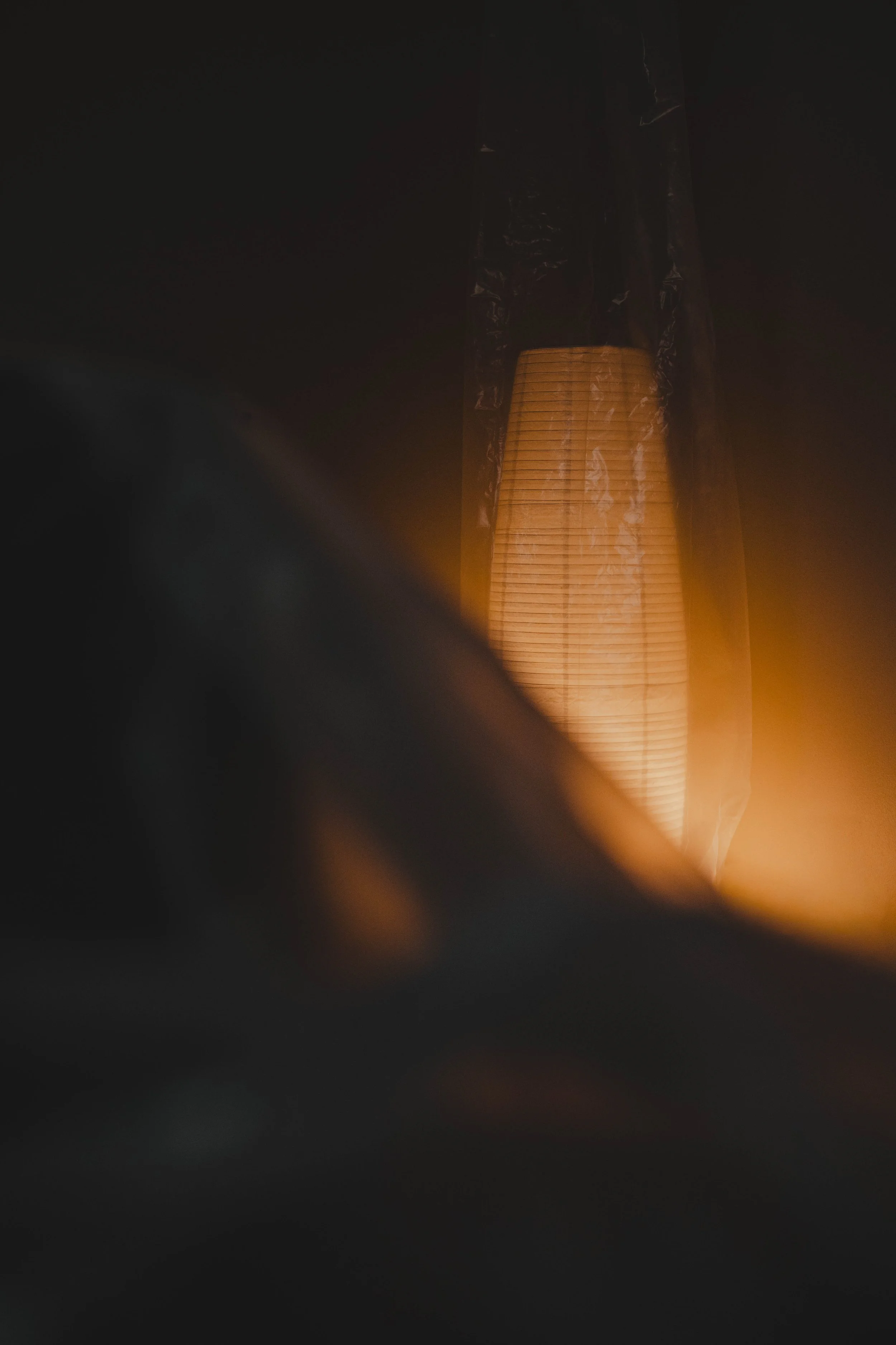 A glowing paper lantern with a black cover at the top, seen in a dark setting.