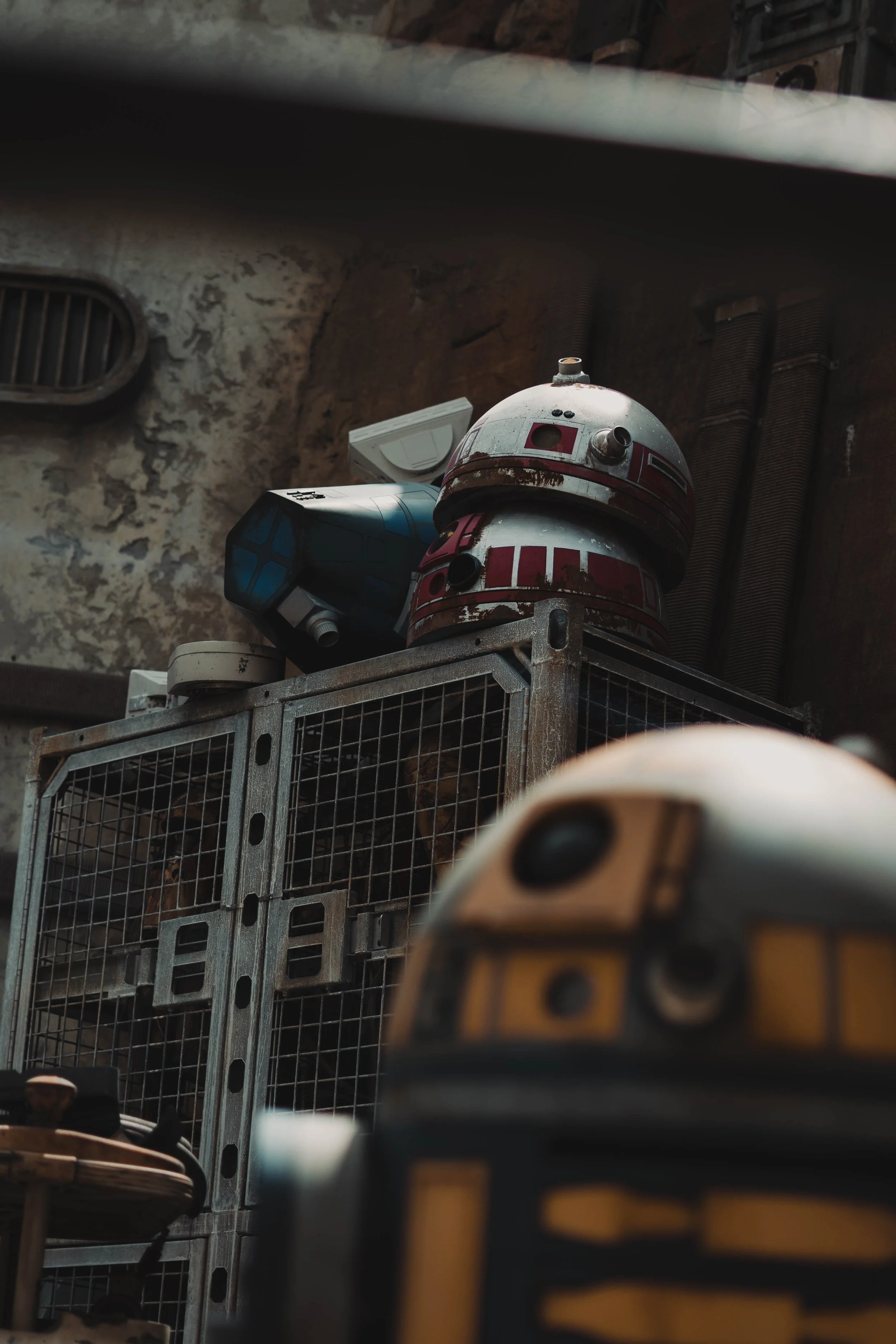 Star Wars-themed droids and robots on industrial shelves in a dimly lit room.