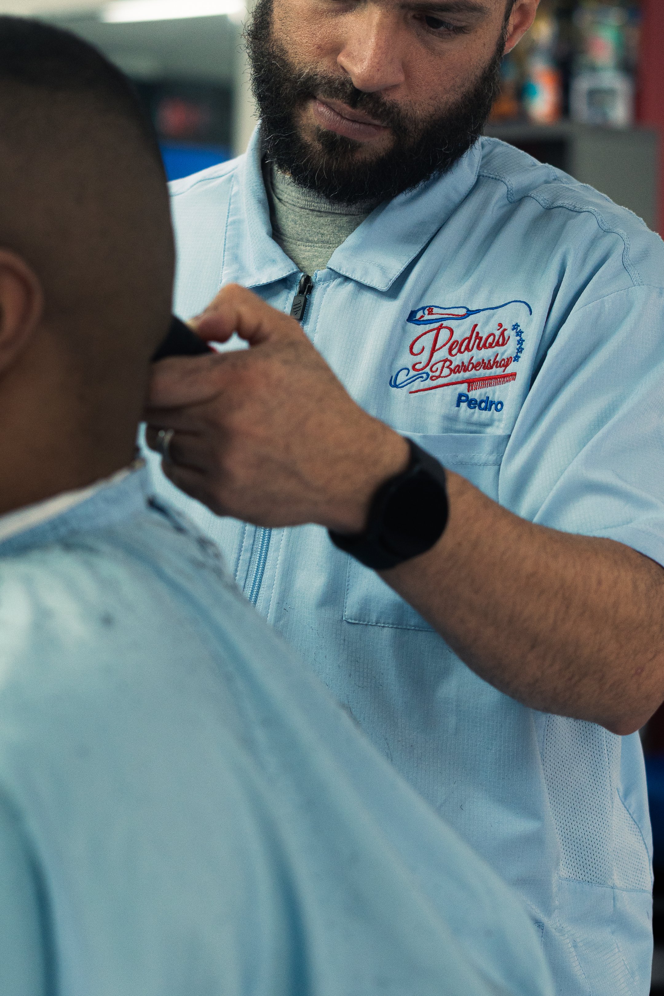 Barber trimming a customer's beard at Pedra's Barbershop