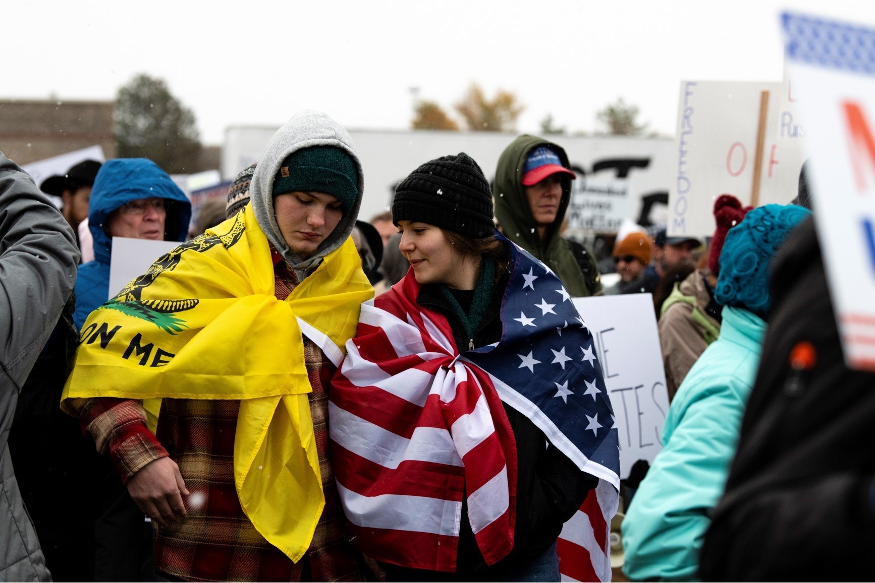Two people wrapped in flags stand in the snow at a protest against vaccine mandates in Fort Collins Colorado Nov. 1. 2021 (Rocky Mountain Collegian)