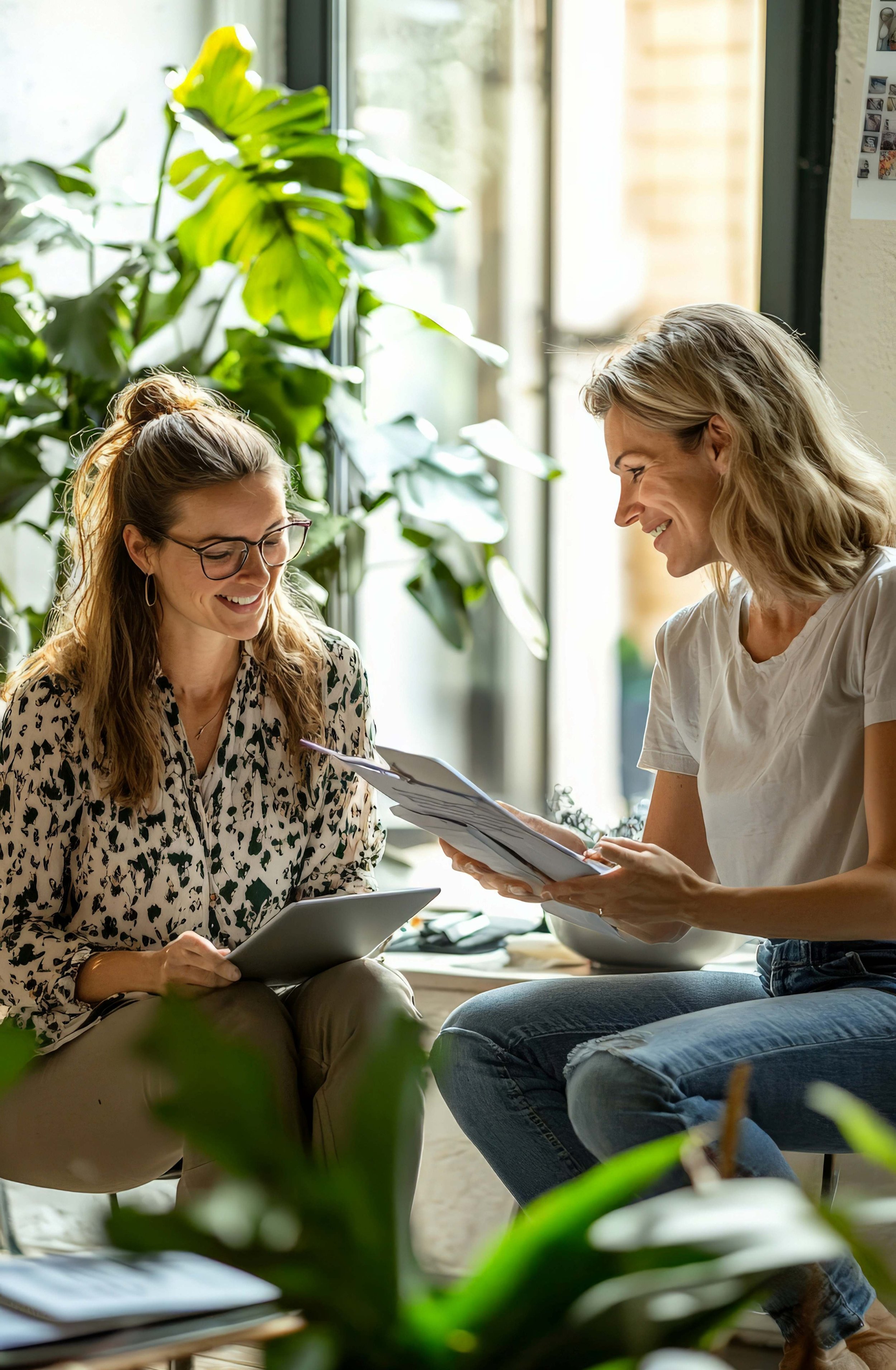 Therapiesitzung. Zwei Frauen in einem vertrauten Gespräch. Ein heller, einladender Raum mit grünen Pflanzen.