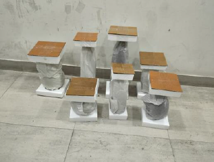 Multiple small tables with wooden tops and concrete bases, arranged in a cluster against a plain wall.