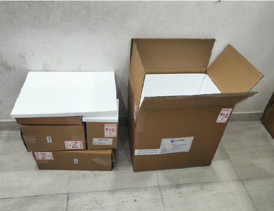 Several stacked boxes, including a large open cardboard box, are placed on a light-colored floor against a plain wall.