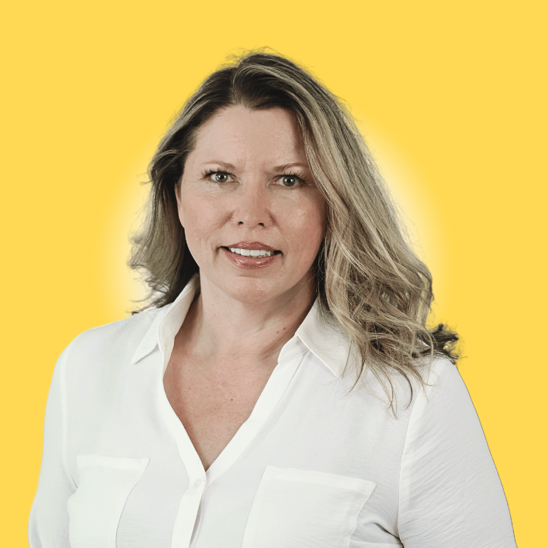 Woman smiling, wearing black blazer, light background