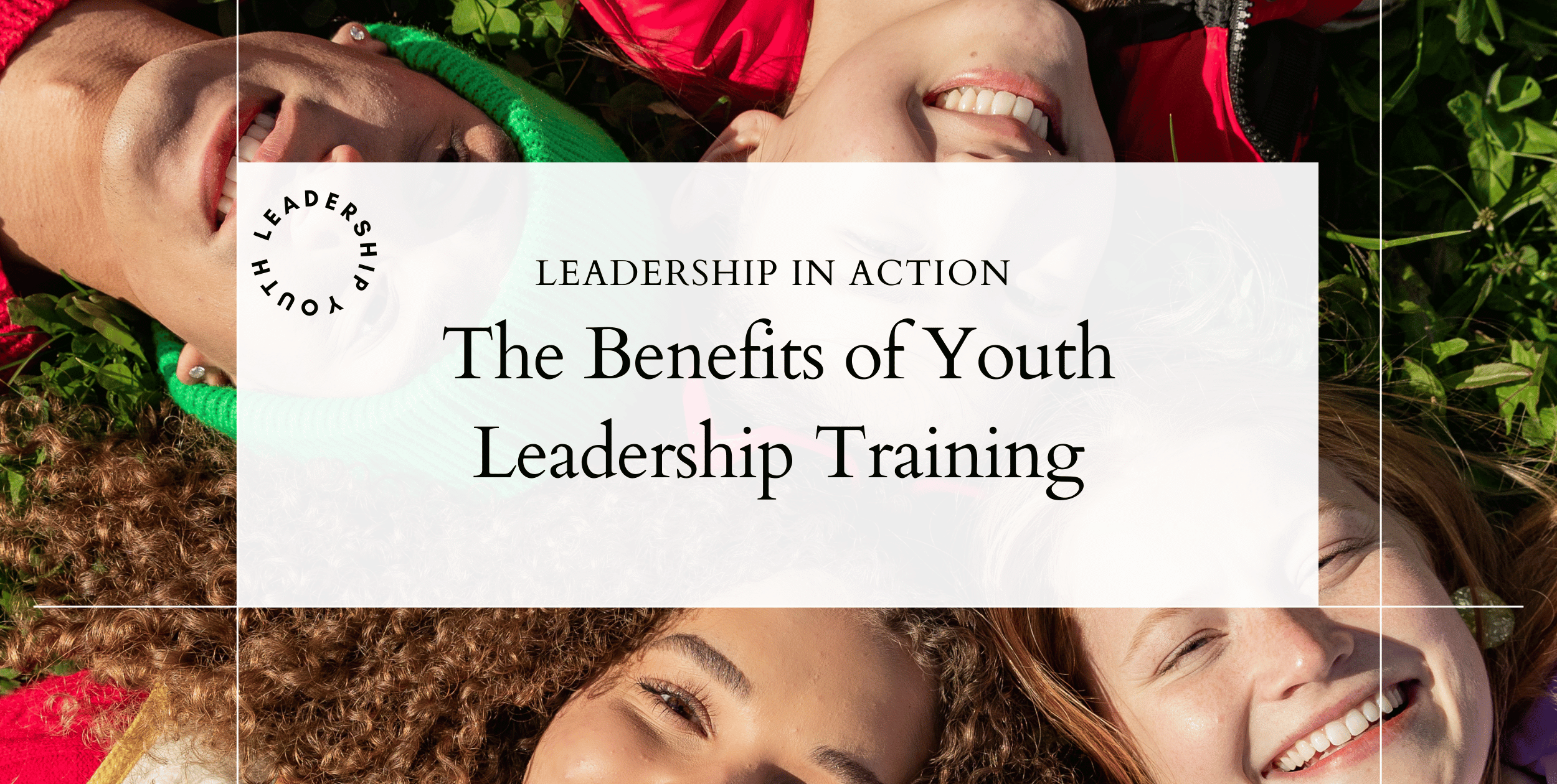 Students laying down on the group, smiling, and looking up at the camera. Their heads form a circle.