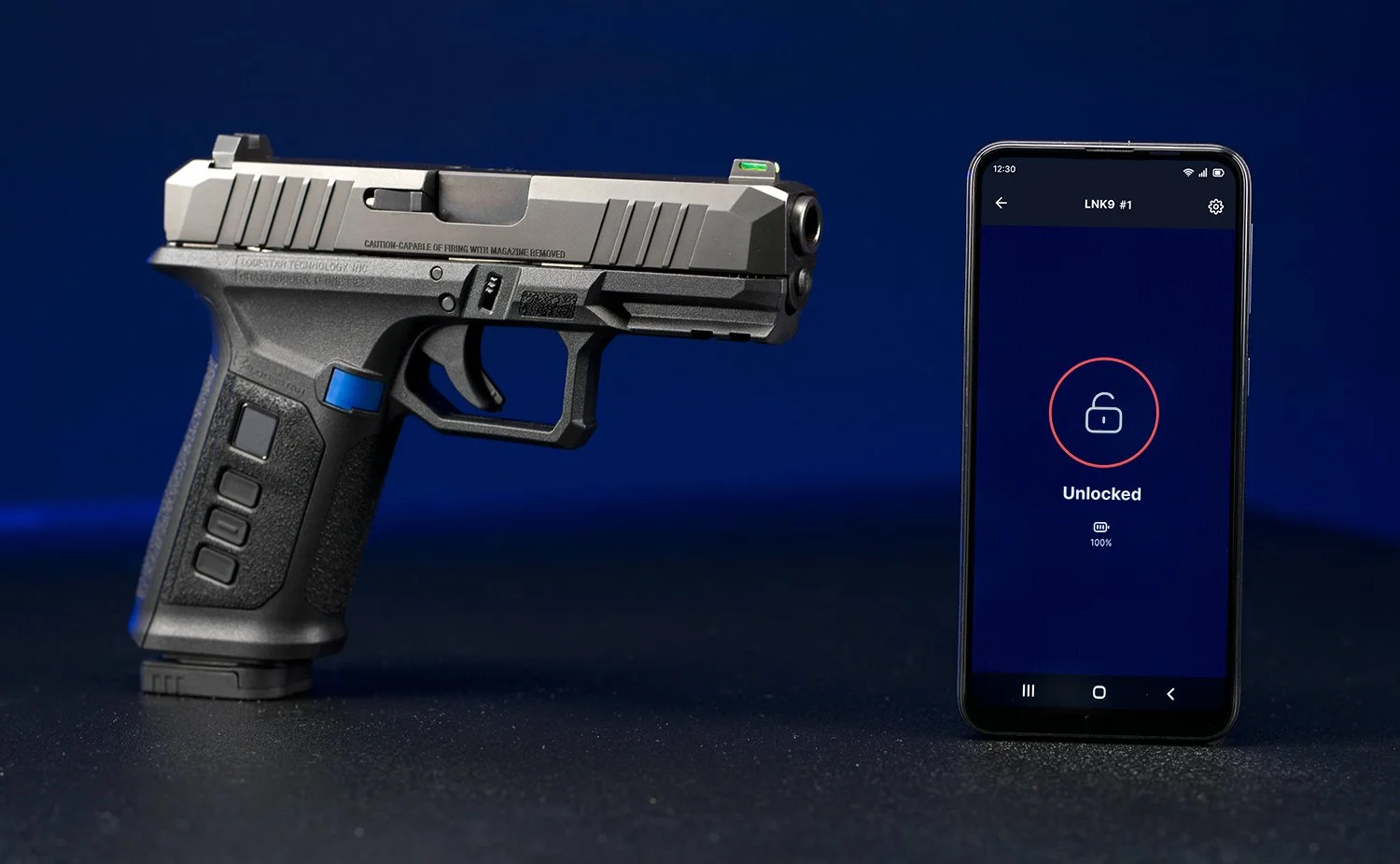 A gray semi-automatic handgun with a blue safety switch and a mounted laser pointer sits next to a smartphone displaying a lock screen with a red circle and a lock icon, indicating the system is unlocked for Lodestar Technology.