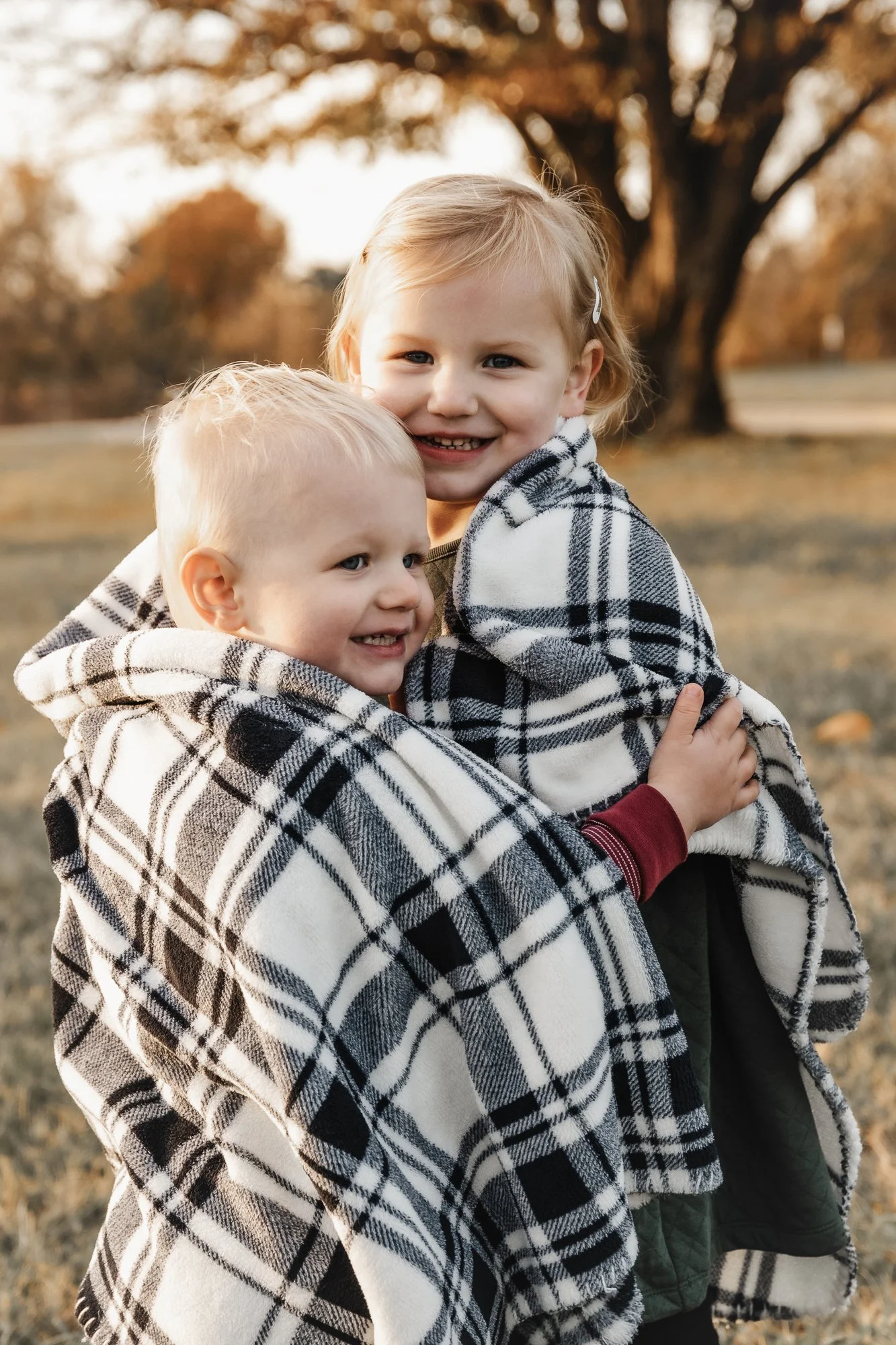 toddler brother and sister wrapped in a blanket hugging at nathanael greene park in springfield mo