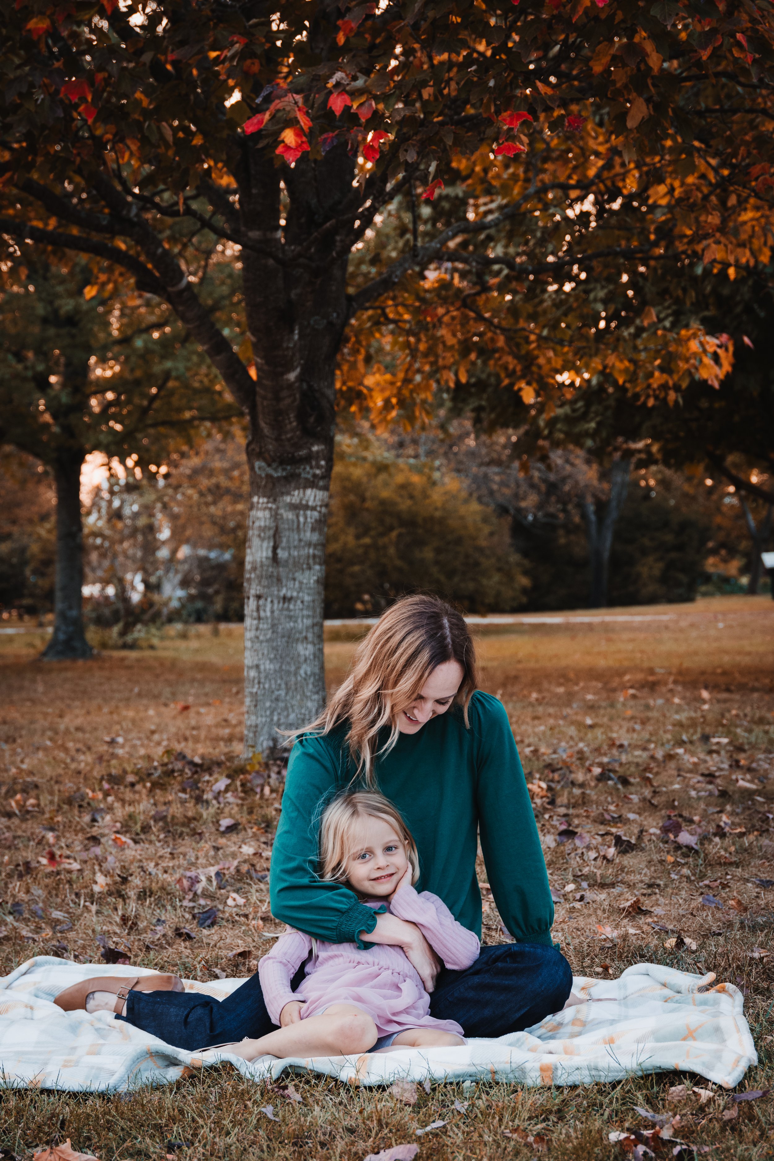 mother and daughter posing on a blanket for fall family photos at nathanael greene in springfield mo