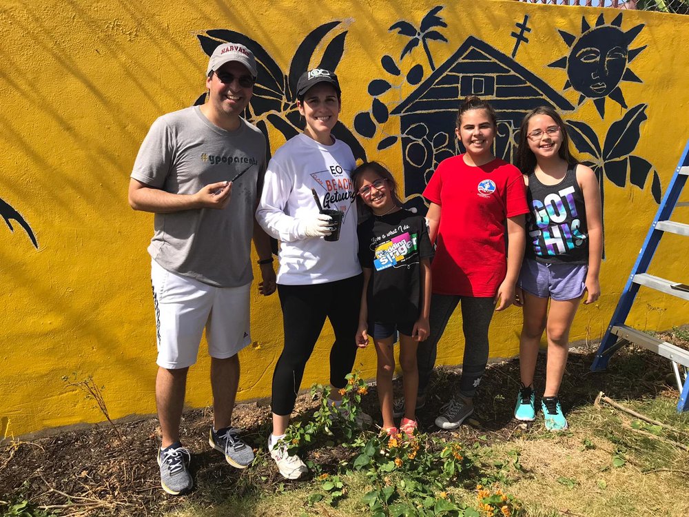  AD&amp;V team members and family posing for picture in front of mural 