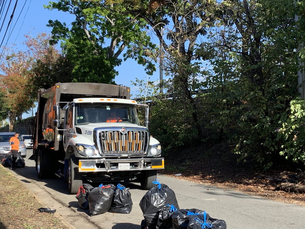  garbage truck picking up trash bags full of debris from cleanup 