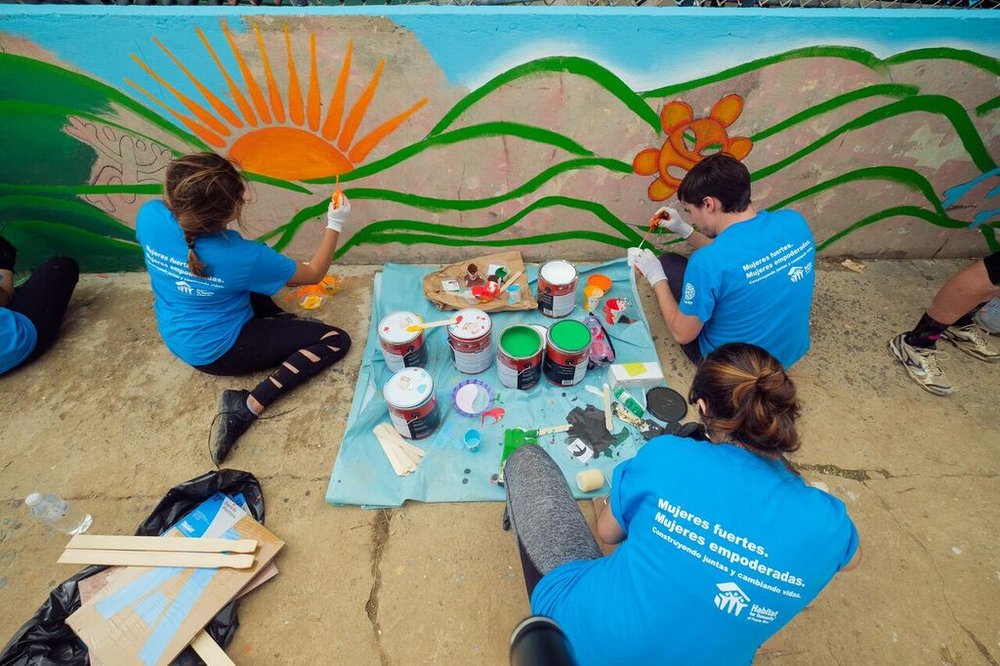  Volunteers painting mural on exterior wall of home 