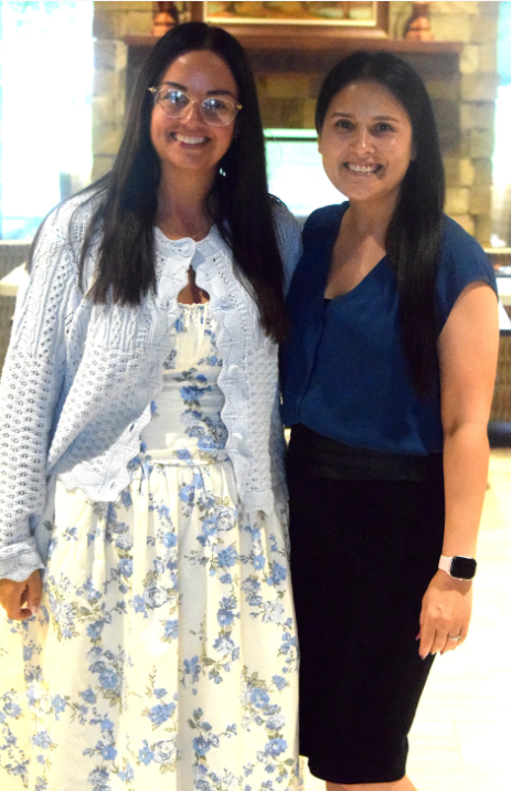 Photo of two women wearing dresses and posing for the camera.