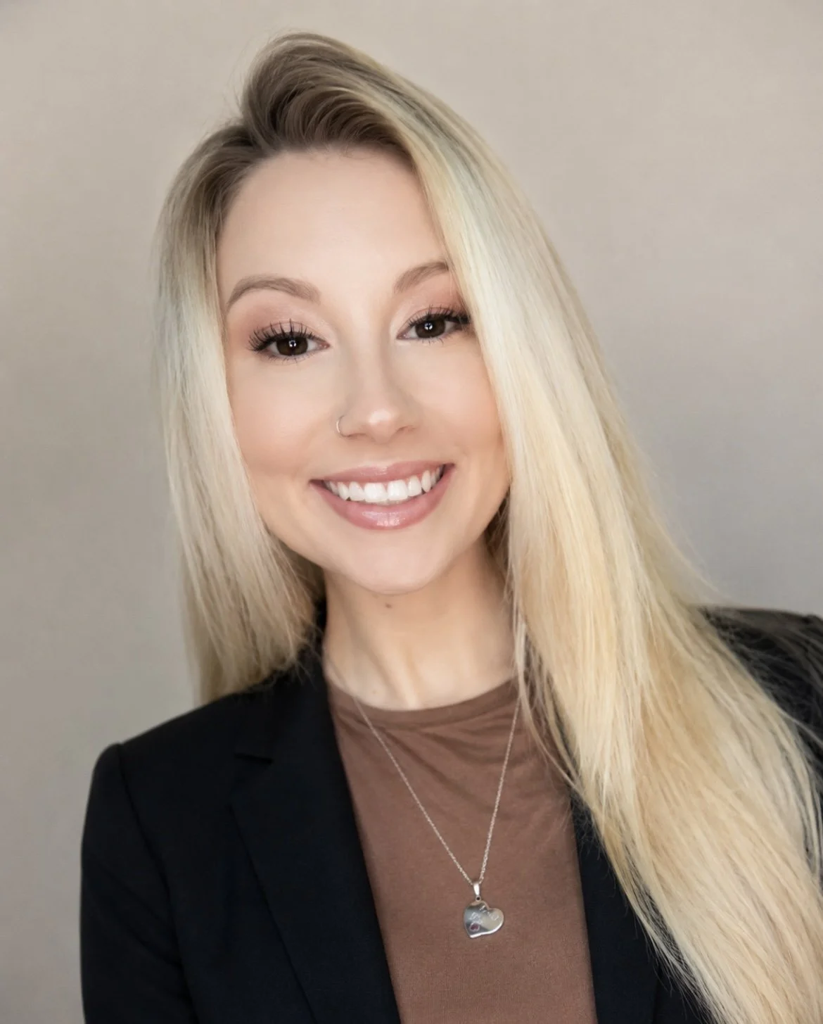 A light-skinned woman with long blond hair and a nose piercing.