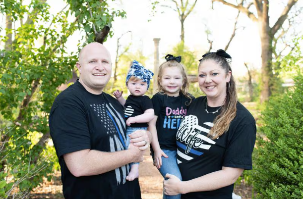Picture of two adults, each holding one child, outside, posing for the camera.