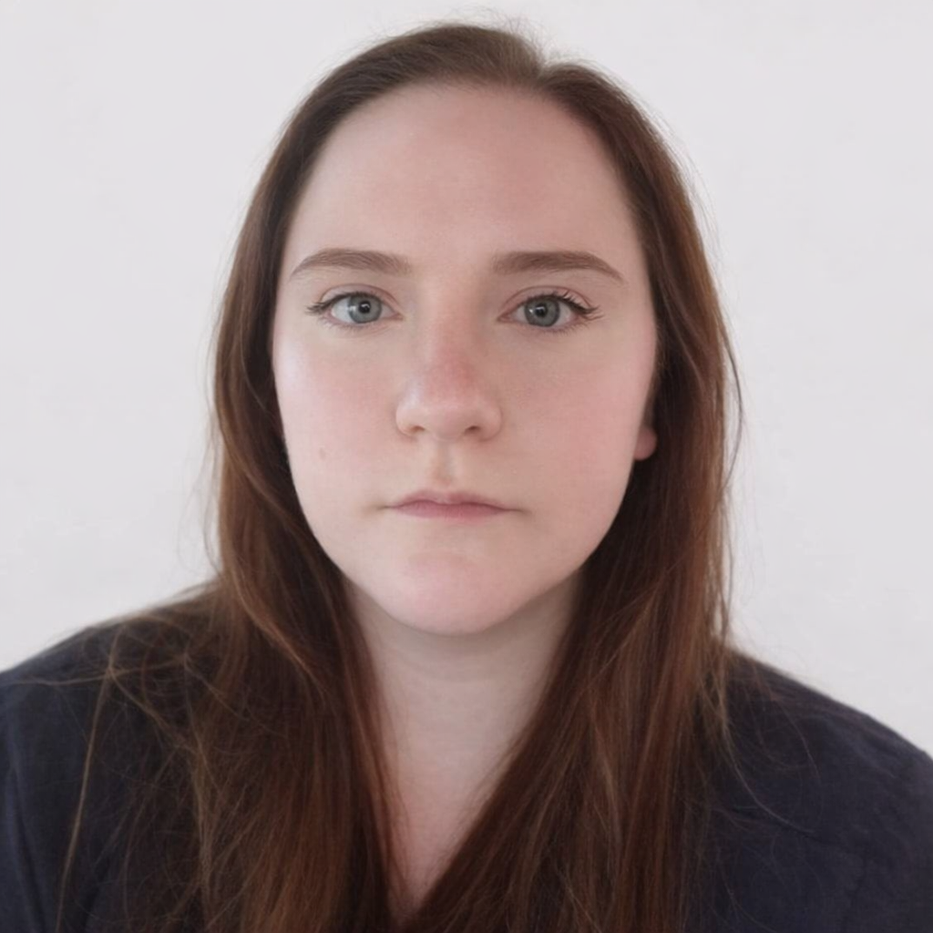 Photo of Erica LoBurgio, a light skinned person with long red hair and blue eyes. Erica is wearing a black shirt.