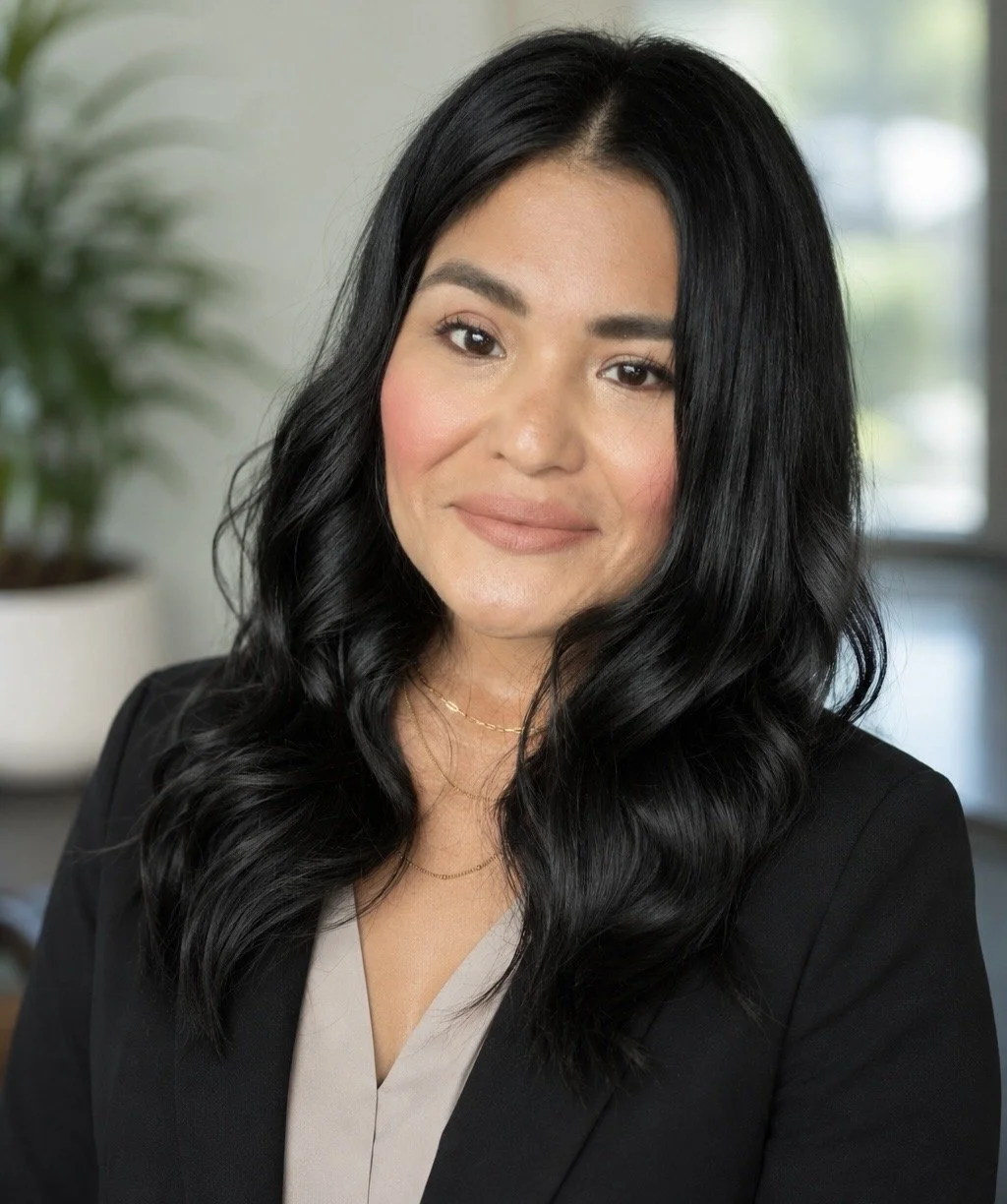 A light-skinned woman with long black hair smiling at the camera.
