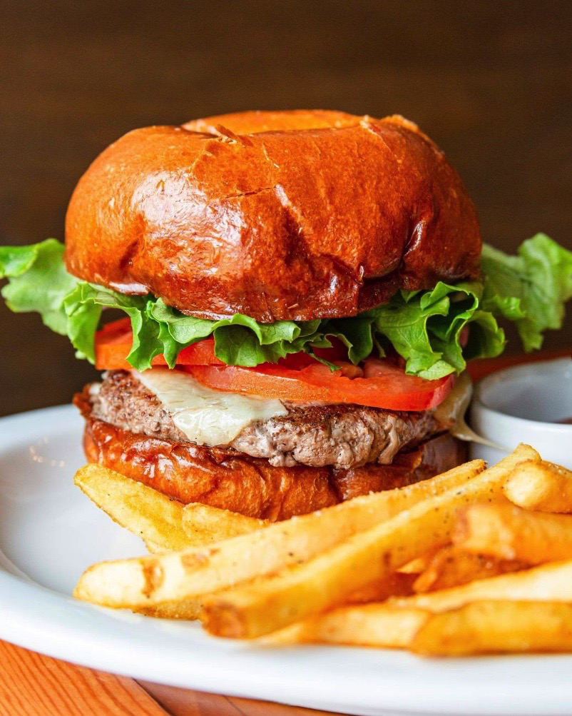 a pub burger sits on a plate with french fries