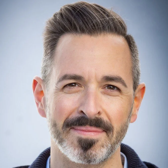 Photo of Rand Fishkin, a white man with dark greying hair and beard in front of a gray background.