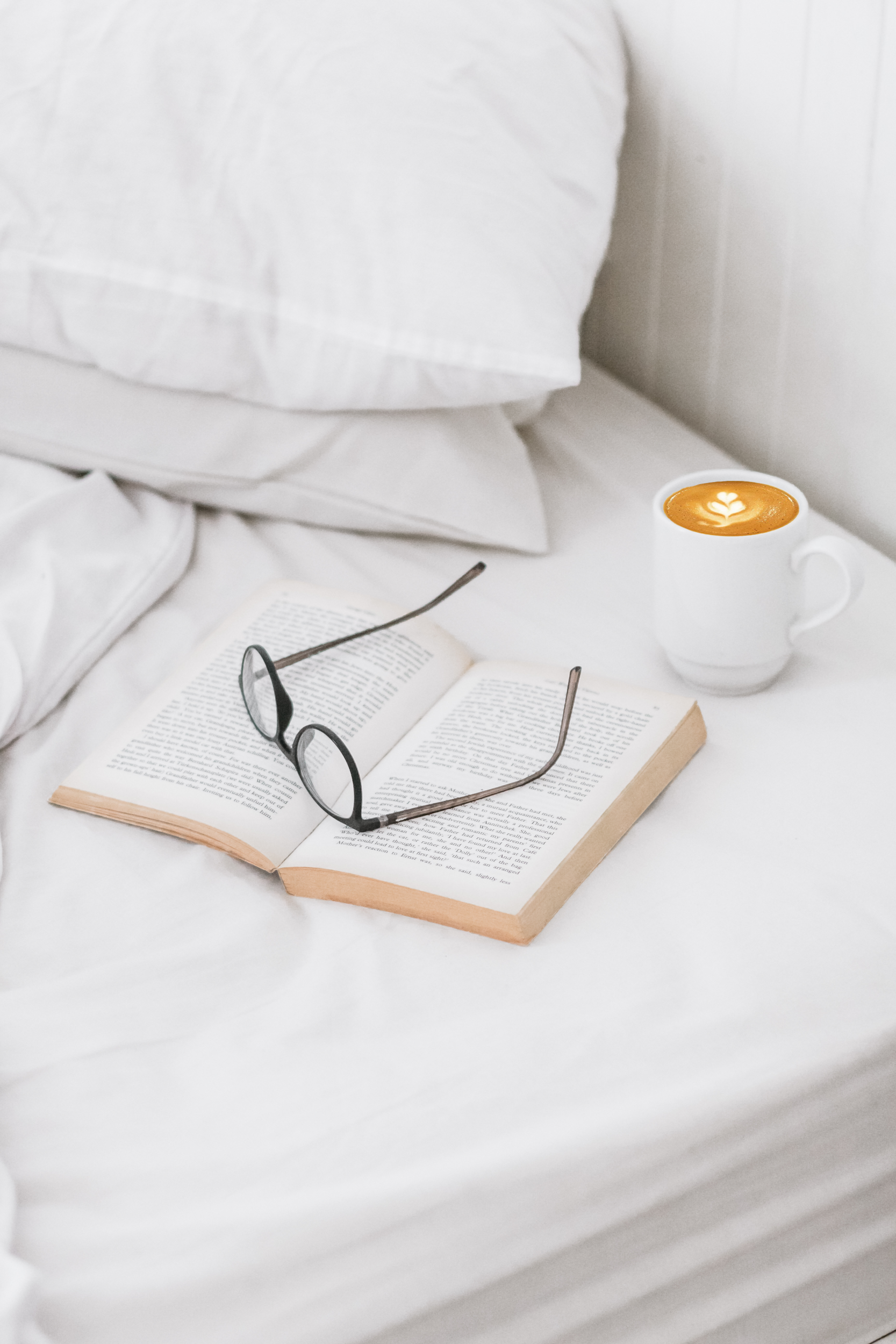 Coffee glasses and book open in white sheets