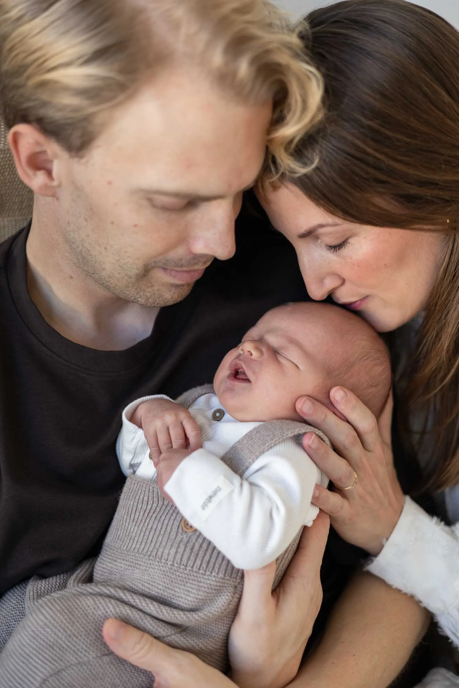 Nyfödd pojke i famnen hos mamma och pappa under nyföddfotografering i Linköping.