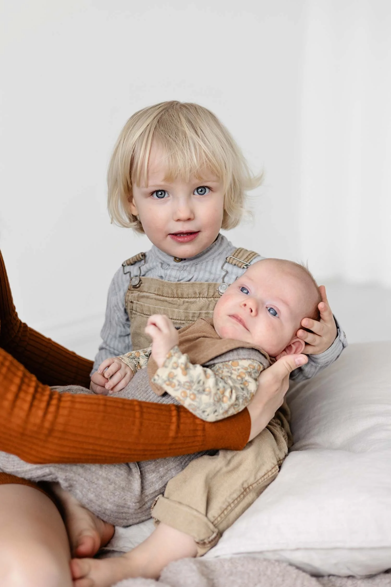 Nyföddfotografering i Linköping. Storebror håller lillebror.