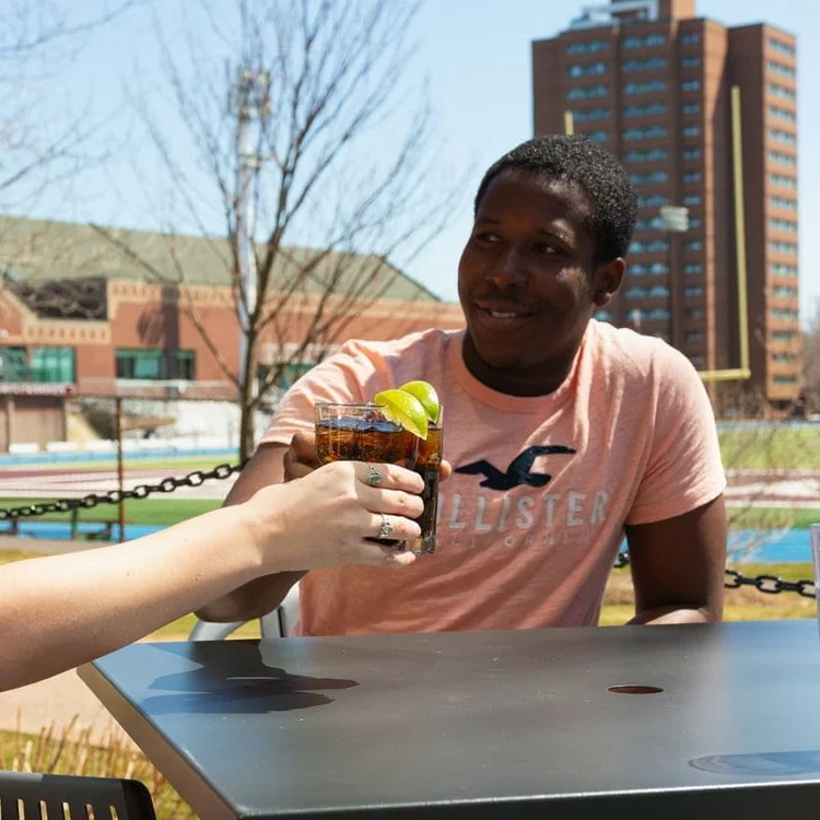 Student raising a glass on the patio