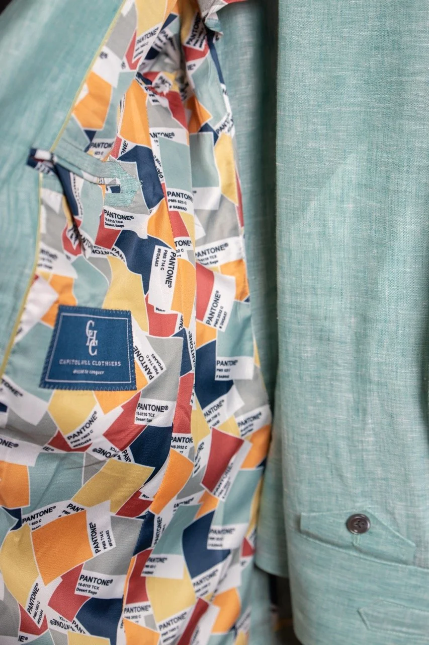 Close-up of a light green blazer with a colorful Pantone-designed lining featuring various shades of red, yellow, blue, and gray swatches. Fabrics for custom suits in Washington, DC
