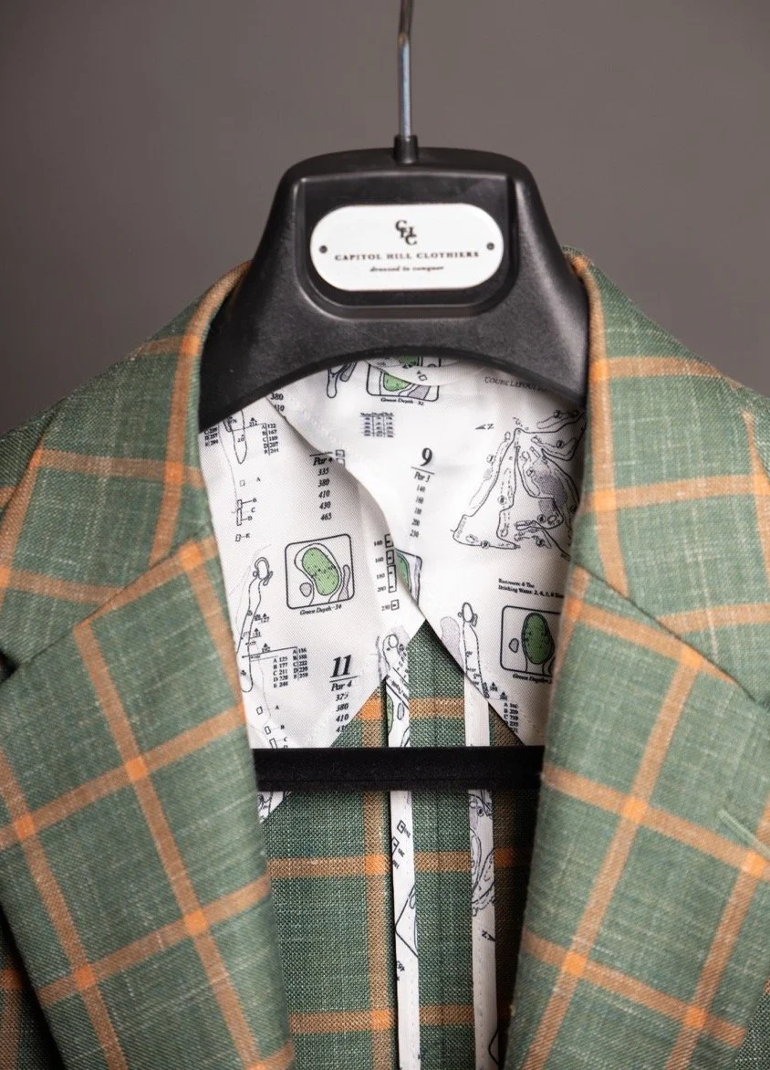 Green plaid suit jacket with illustrated lining, hanging on a Capitol Hill Clothiers hanger. Fabrics for custom suits in Washington, DC