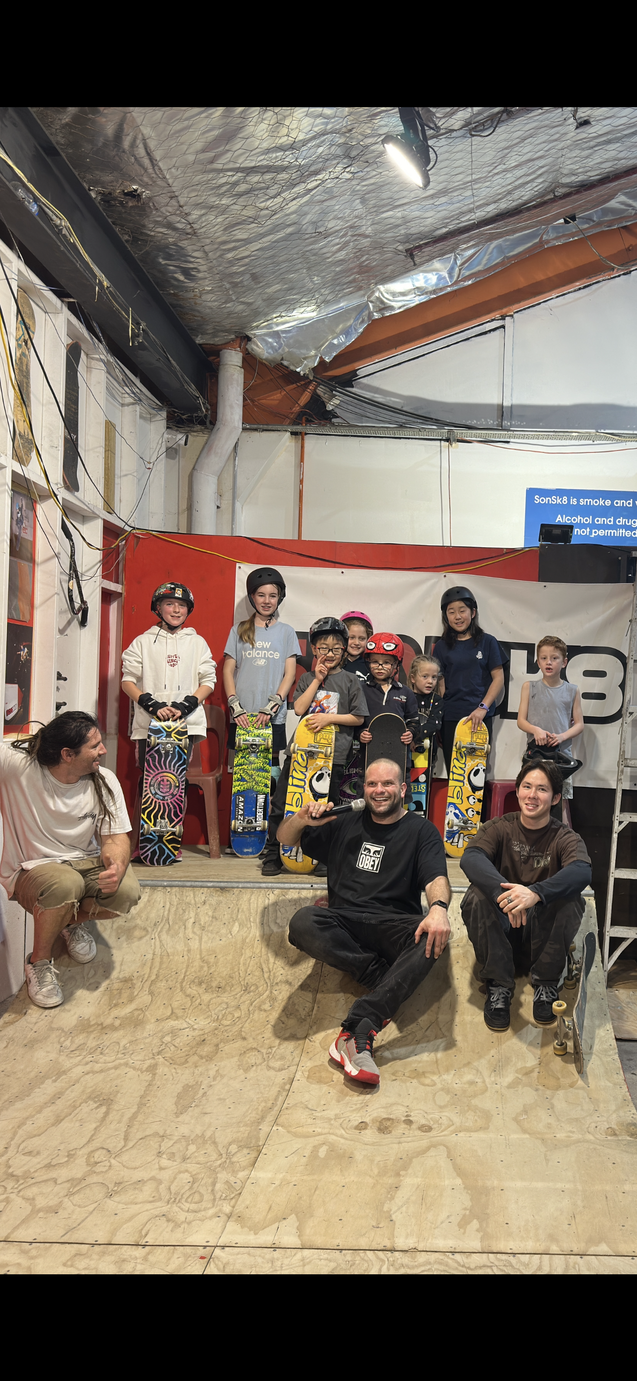 Group of kids and adults with skateboards on an indoor skate ramp