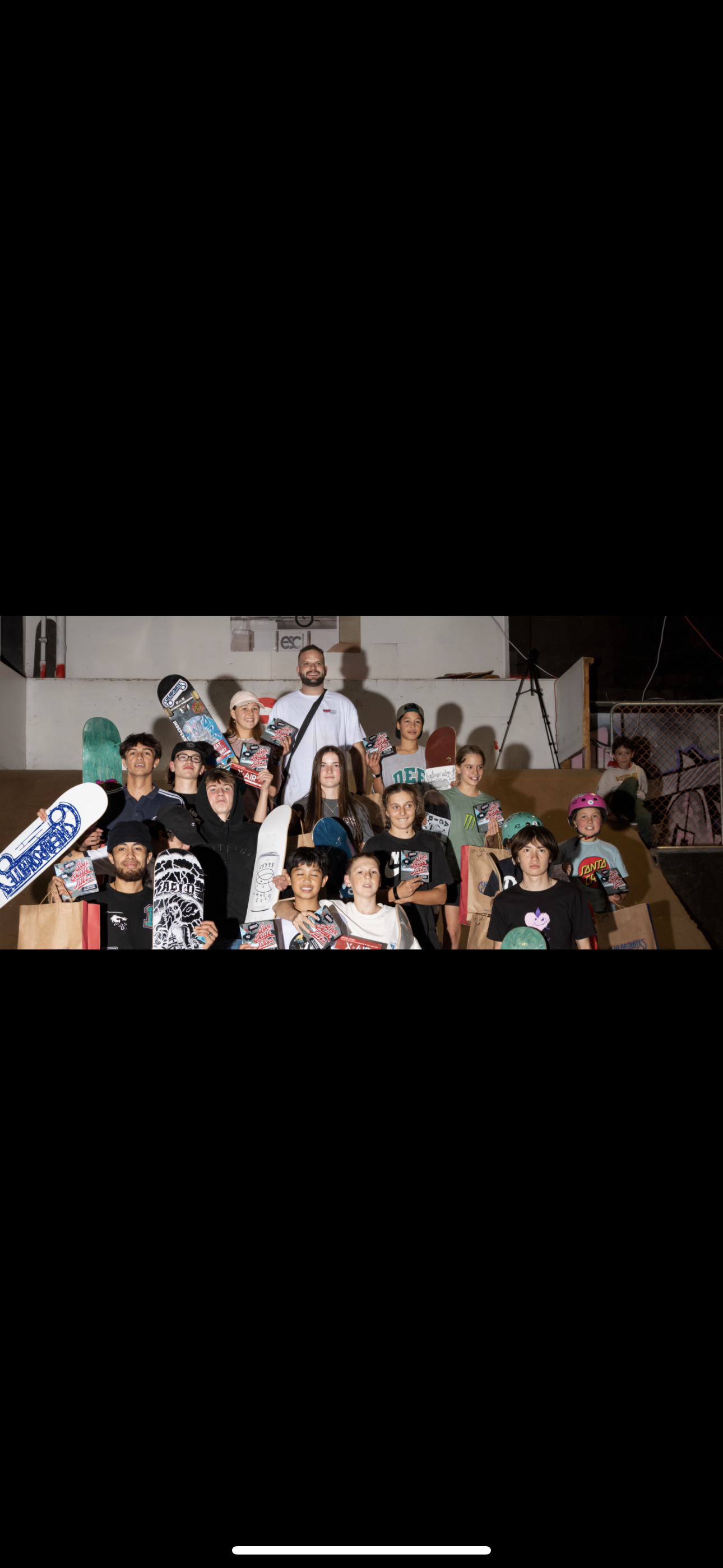 Group of people holding skateboards and certificates, standing on a ramp, surrounded by skateboard-themed items.