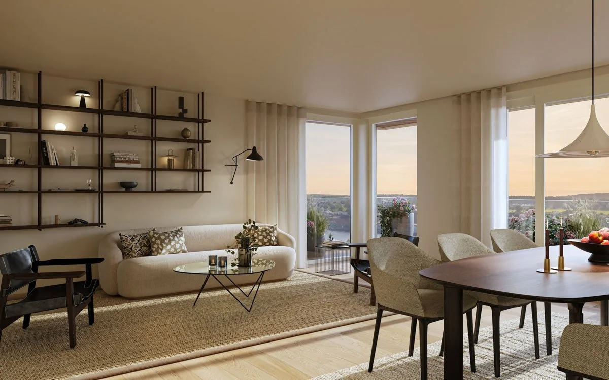 Lyst stue med åpen layout, gulv i tre, stor sofa med puter, spisebord med seks stoler, store vinduer med utsikt over natur, og hyller på veggen med dekorative gjenstander.
