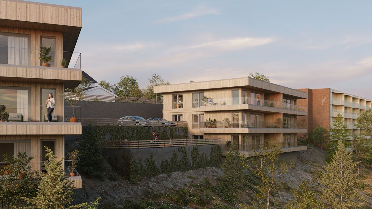 Moderne leilighetskomplekser på en skråning med balkonger, omgitt av trær og med parkeringsplasser.