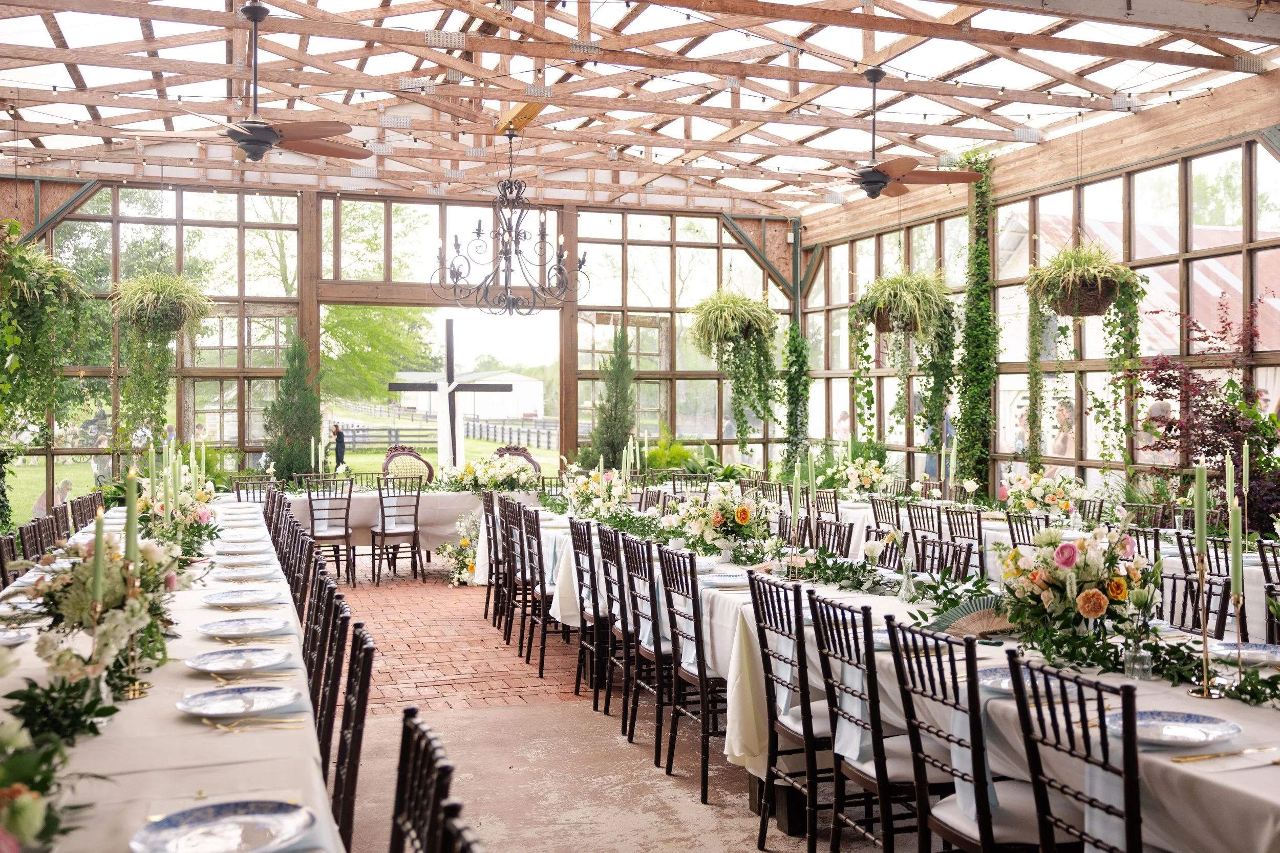 Wild Daisy Farm conservatory greenhouse wedding reception setup with chiavari chairs, elegant tablescapes, hanging plants, and natural garden atmosphere in Molena Georgia