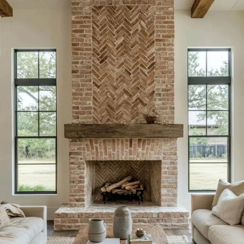 Brick fireplace with a wooden mantel and black firebox opening, partially constructed with construction materials inside.