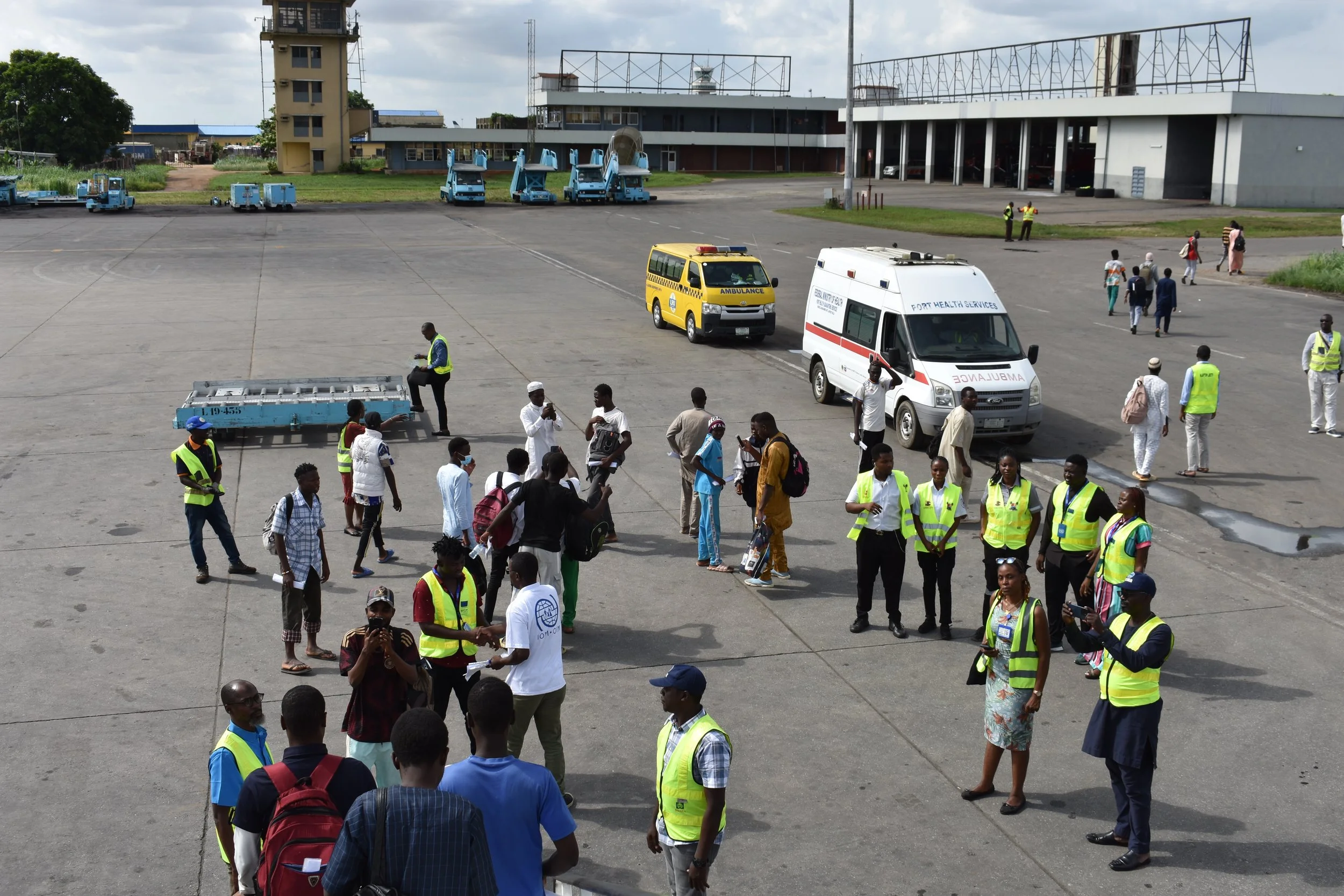 Migrants and IOM staff on the tarmac.