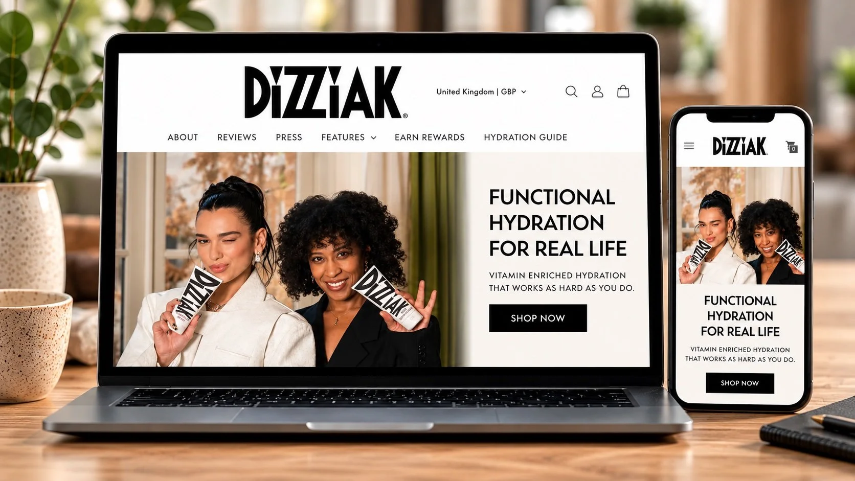 Laptop and smartphone screens displaying the DIZZIAK website with women holding DIZZIAK skincare products, set on a wooden desk with decorative vases and a notebook.