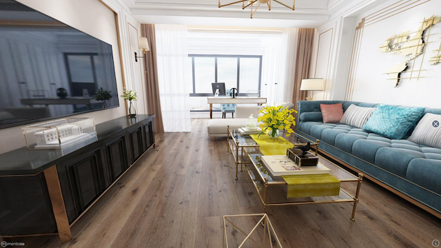 Modern living room with a large television, a patterned blue sofa with cushions, a glass coffee table with yellow accents and flowers, and a desk near a large window with sheer curtains.