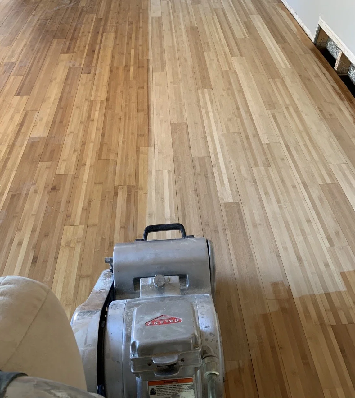Floor sander in use on wood floor, half sanded