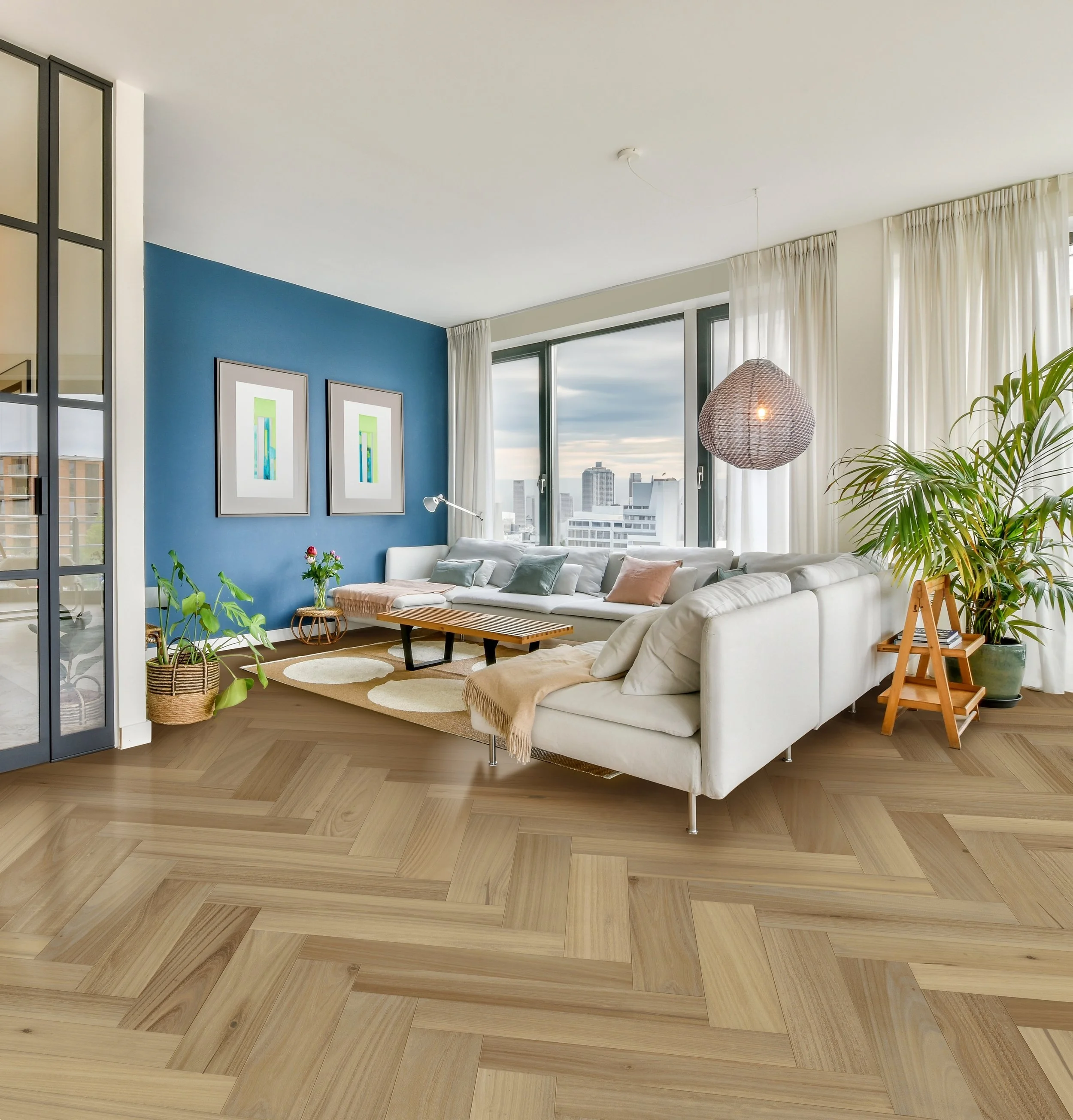 Modern living room with large window view, white sectional sofa, wooden flooring, green plants, blue accent wall with framed artwork, and a woven pendant light.