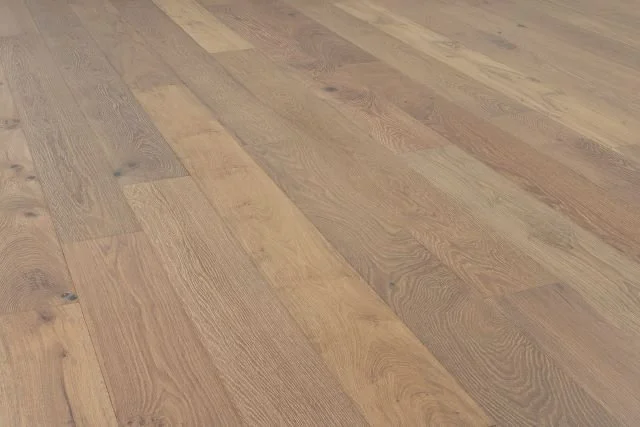 Close-up of a wooden floor with planks in various shades of light and medium brown.