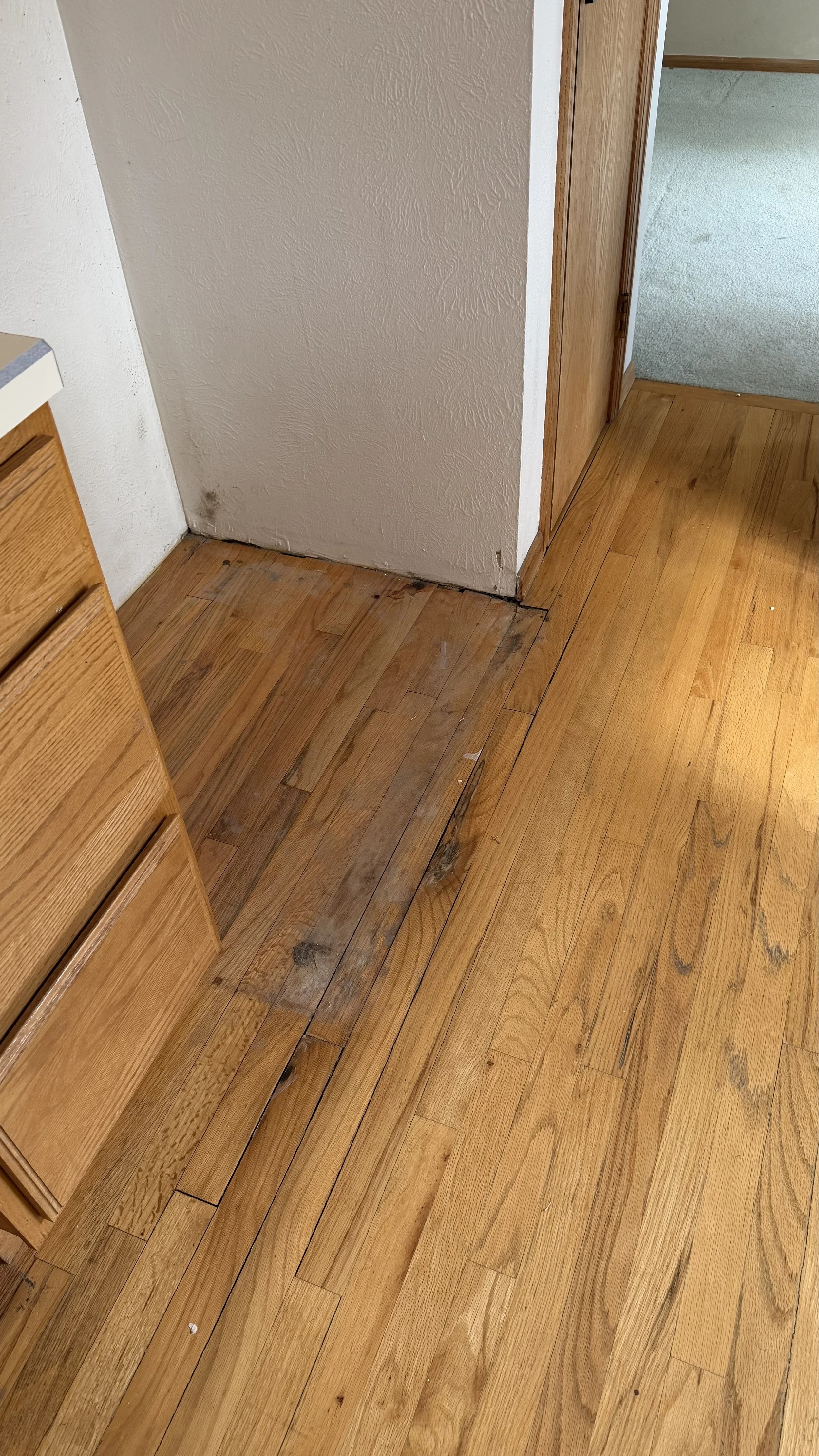 Hardwood floor showing water damage with discoloration and surface deterioration prior to repair and restoration by Express Hardwood & Flooring.