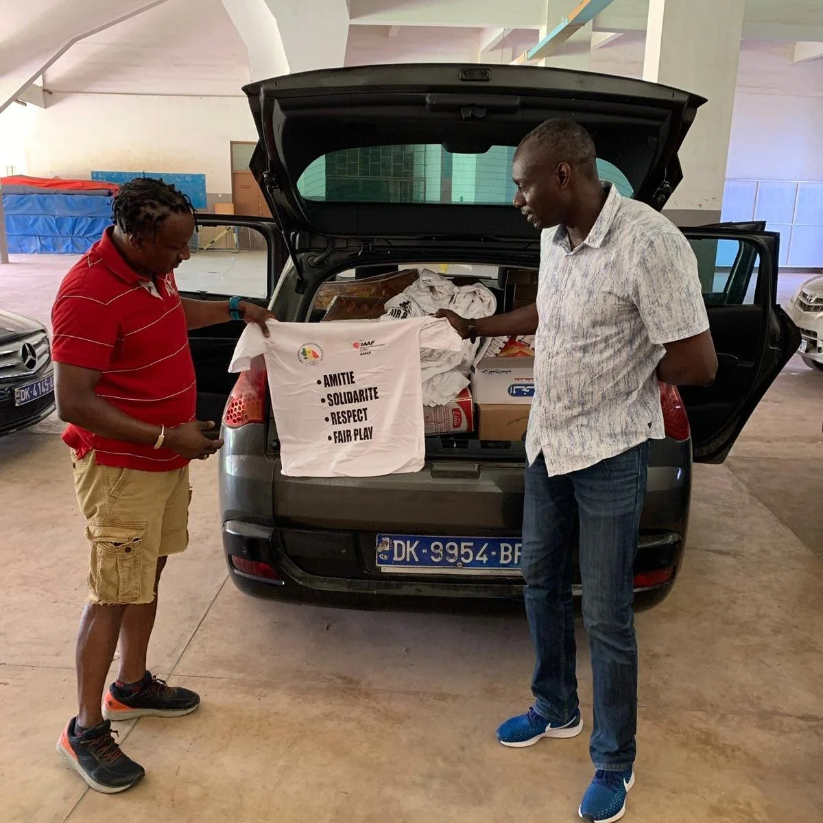 Amadou Dia Ba, Olympic Games medalist, delivers goods to Eric Lopez, Sponsor Zone President for the Summer Camp..